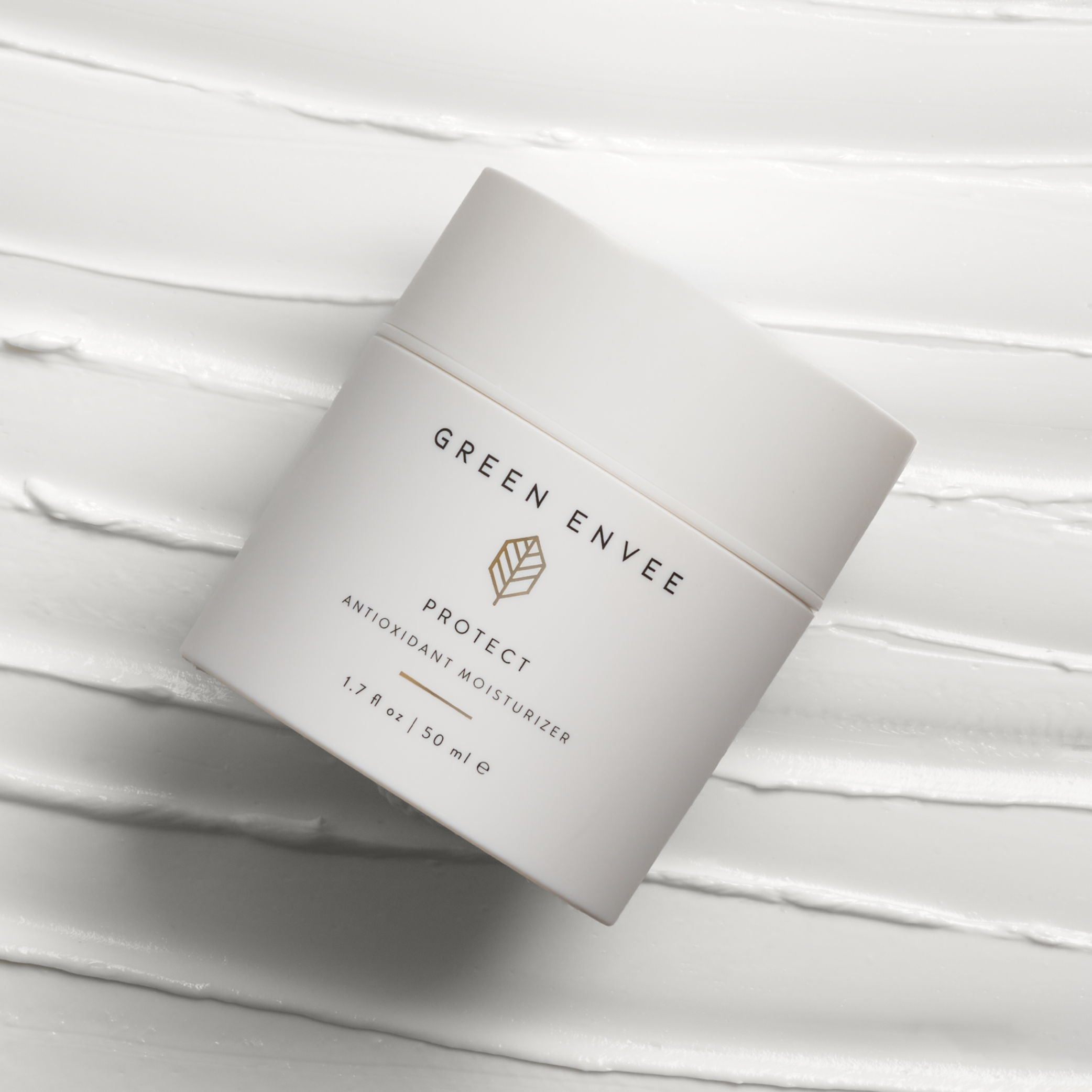 green envee protect antioxidant moisturizer laid on top of cream that looks like icing. 