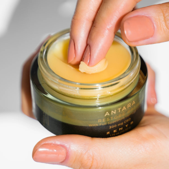 fingers dipping into the antara restore body balm from heaven on earth aspen 
