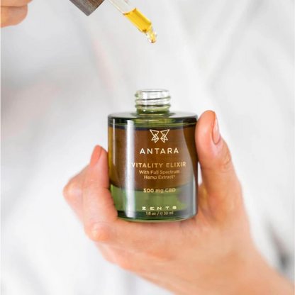 hand holding the antara vitality elixir with a dropper above it sold at heaven on earth aspen spa 