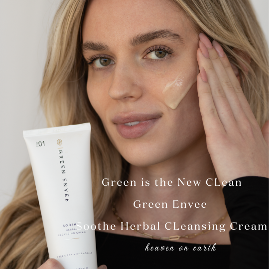 image of a model holding the green envee soothe herbal cleansing cream and  swoosh of the cleansing cream on her cheek.