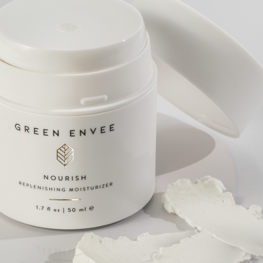 white jar of the green envee nourish replenishing moisturizer at heaven on earth aspen with its cap and moisturizer around the bottle