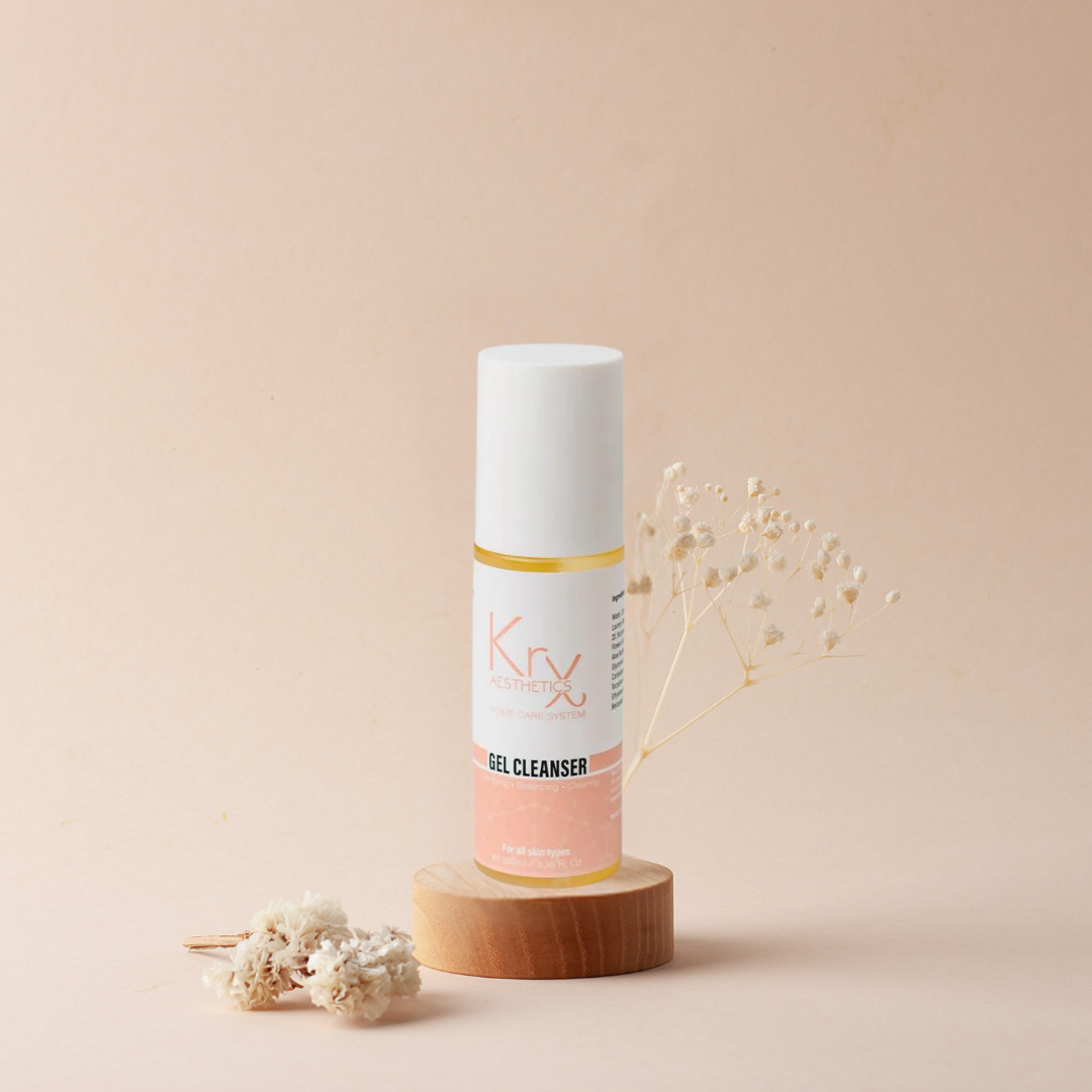 krx glow gel cleanser from heaven on earth on a wood pedestal with white flowers around it 